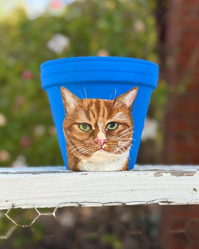 Hand-painted orange tabby cat on a blue clay pot