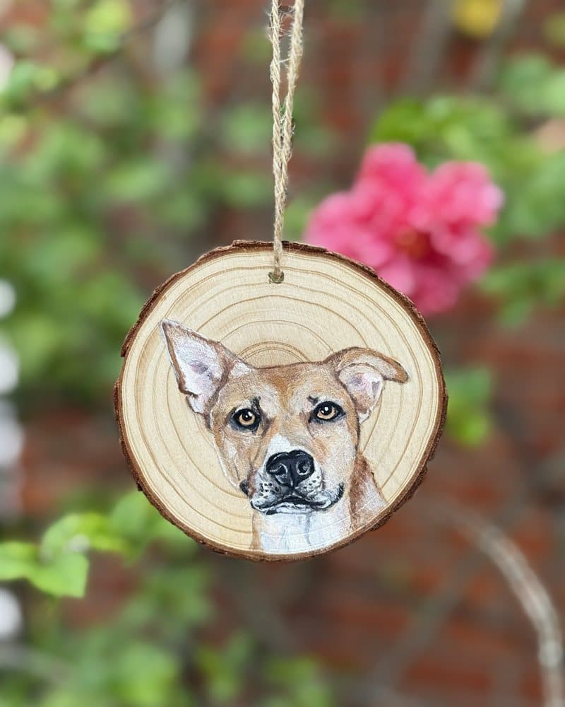 Hand-painted tan dog on a wood round ornament, framed by pink flowers